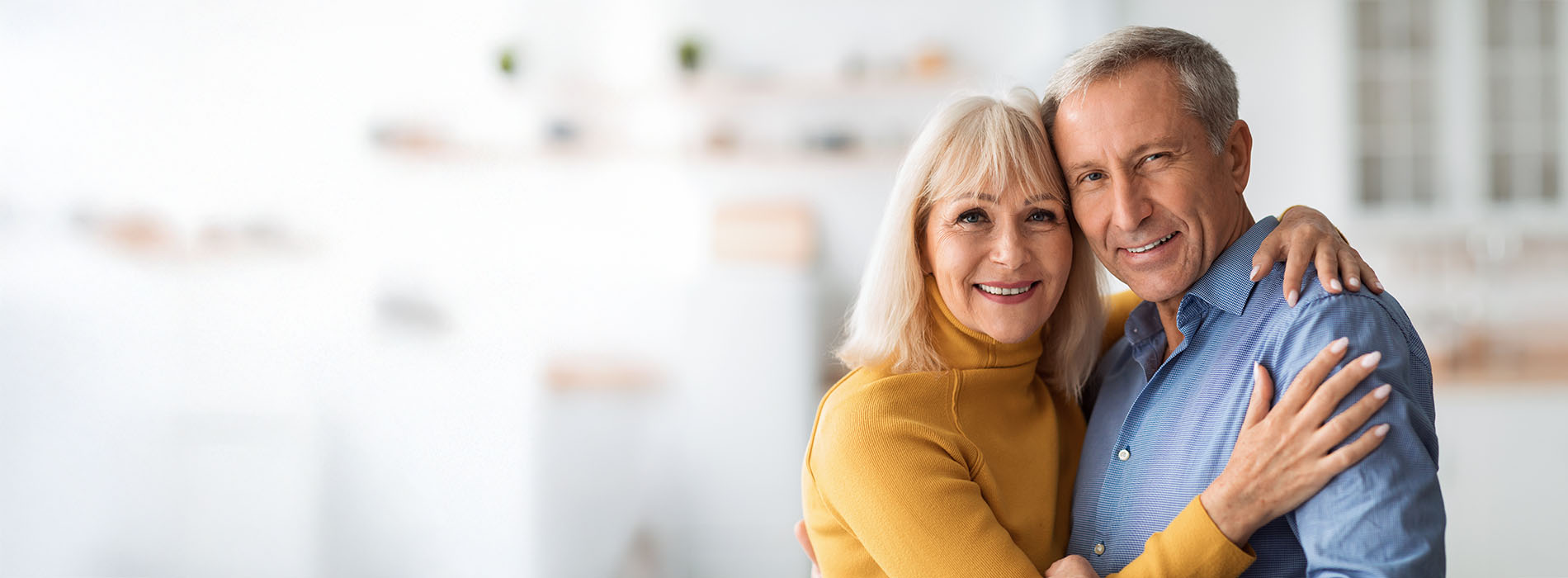 An elderly couple embracing each other warmly.