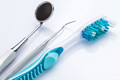 The image shows a set of dental tools including a toothbrush with blue bristles, dental floss, and a pair of tweezers, all displayed on a white background.